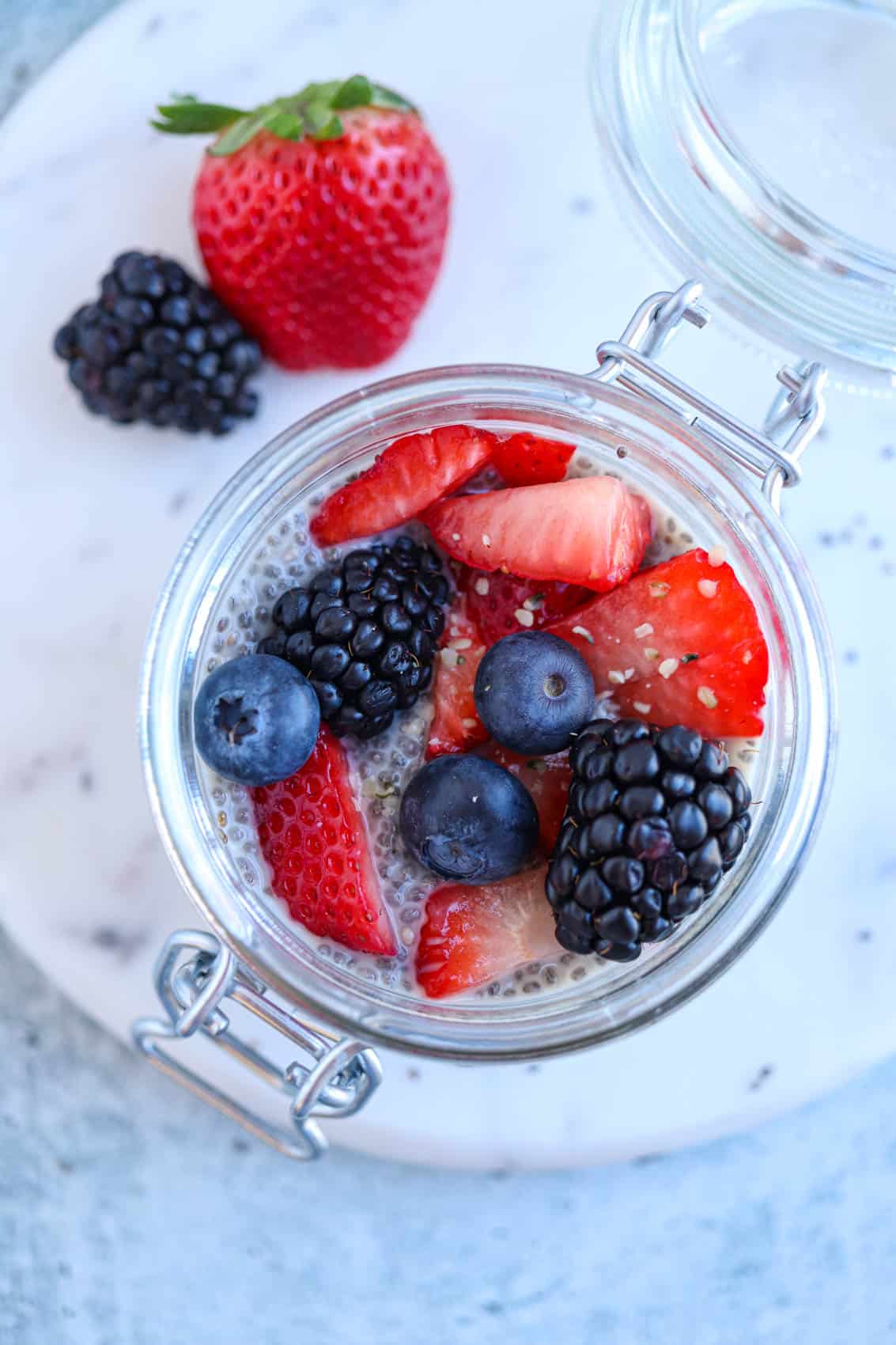 overhead view of chia pudding topped with berries in a small mason jar.
