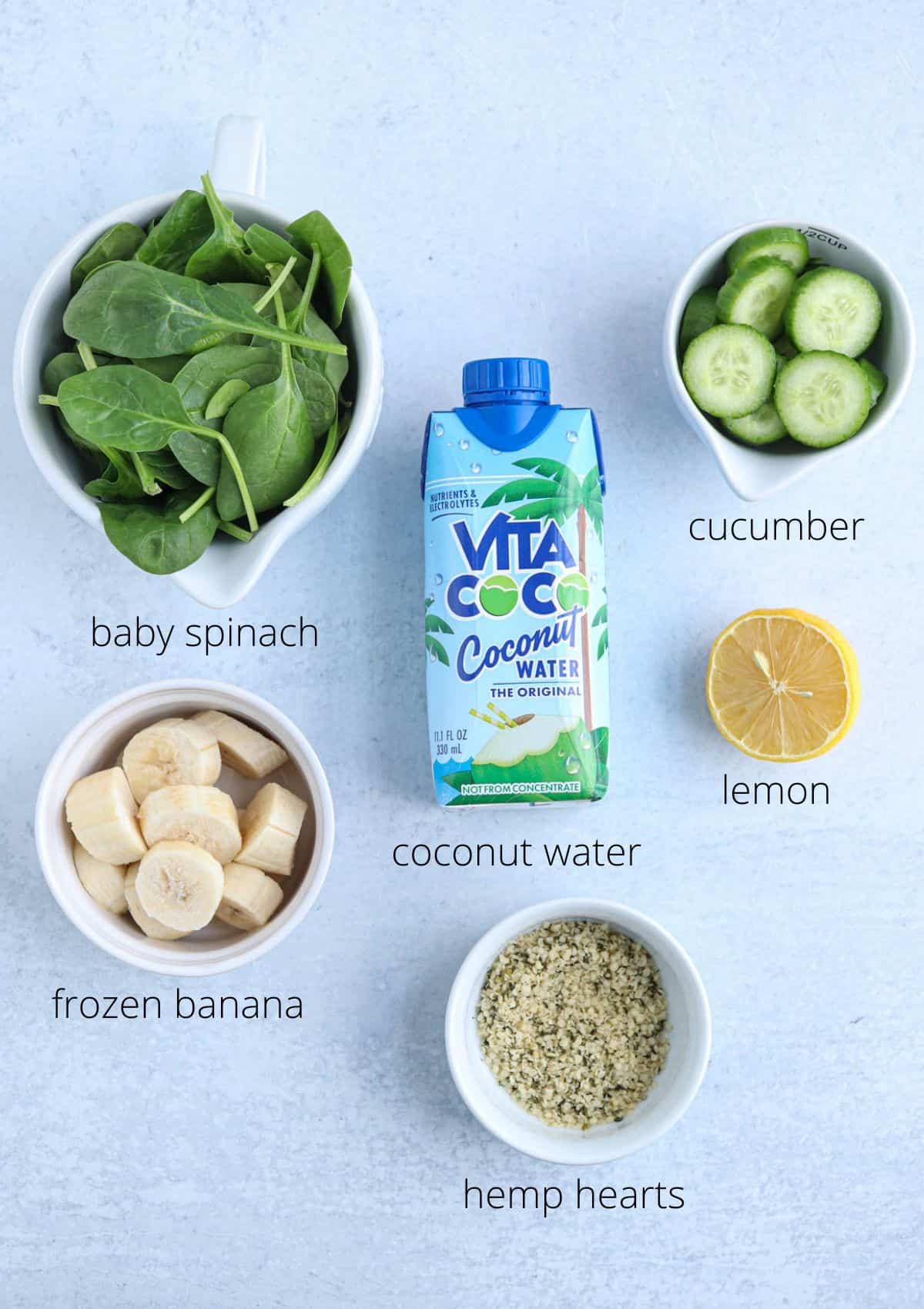 Ingredients for making green spinach cucumber smoothie on light gray surface with captions.
