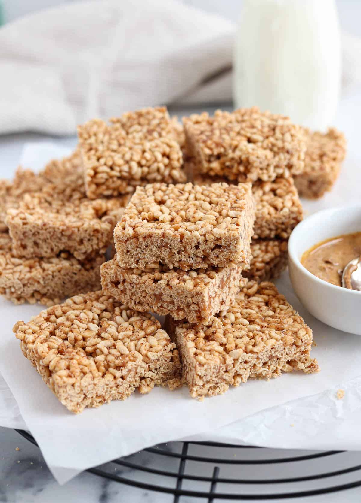 healthy rice krispie treat squares on white paper on top of a black cooling rack. 