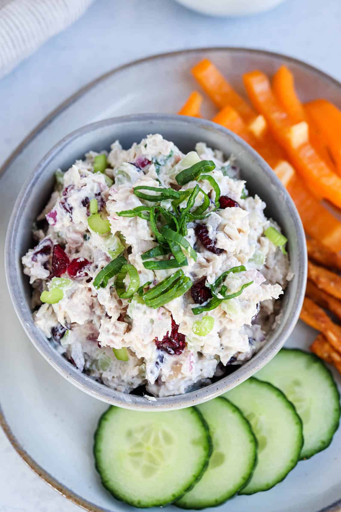 overhead view of creamy chicken salad in a small gray bowl with chopped scallions on top.