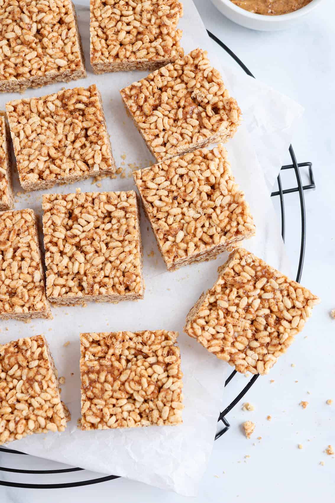 healthy rice krispie treat squares on white paper on top of a black cooling rack, close up.