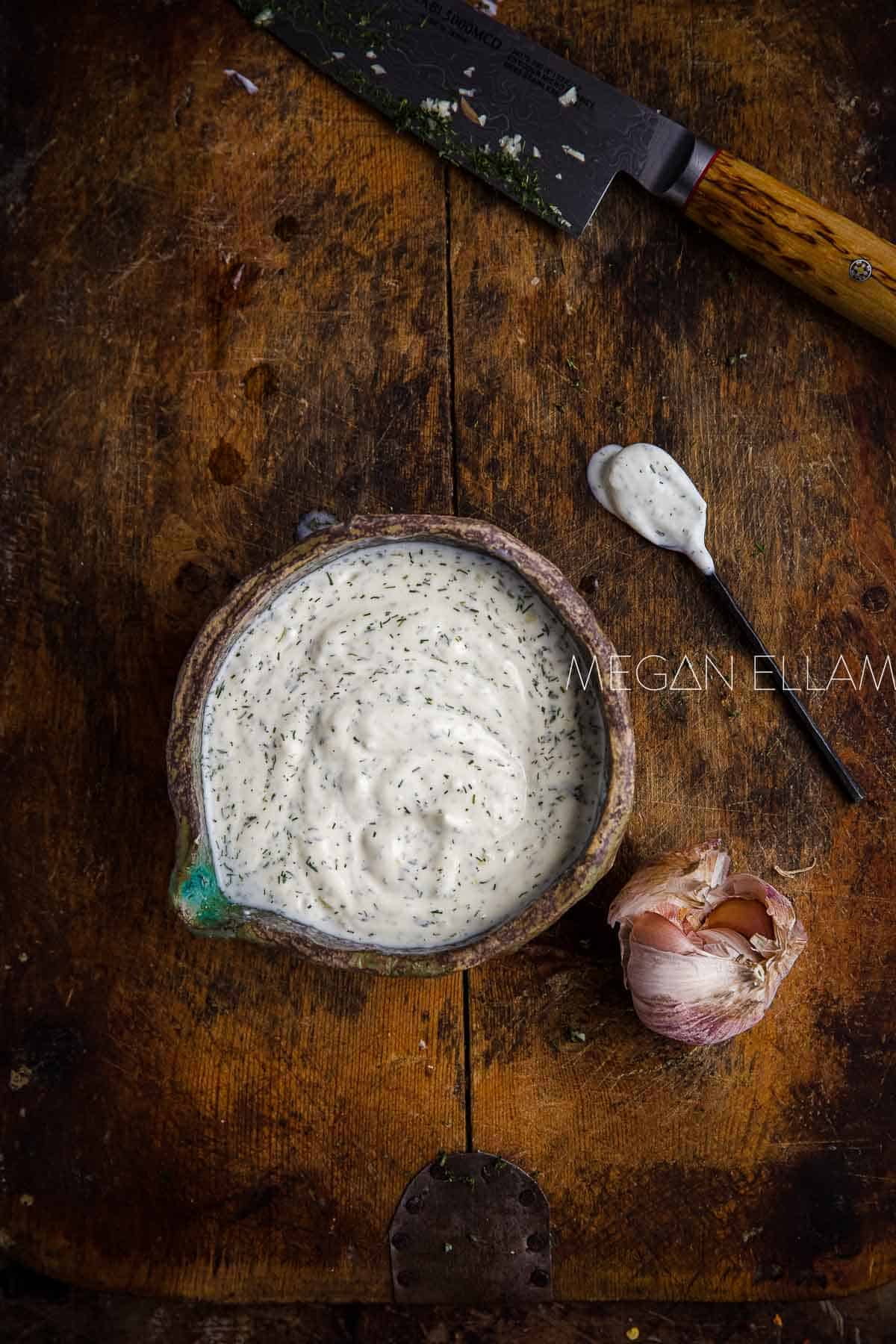 yogurt sauce with dried herbs in a wooden bowl on wooden background.