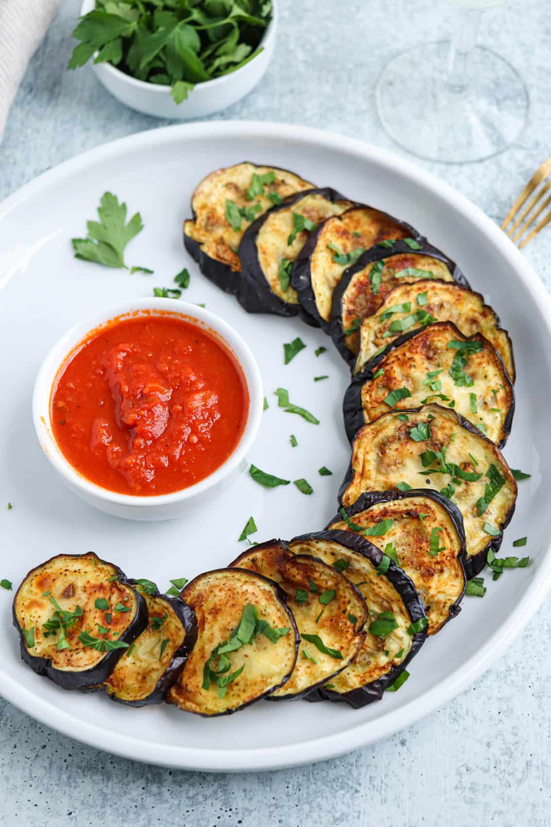 air fryer roasted eggplant slices on a white plate with a side of Marinara sauce.