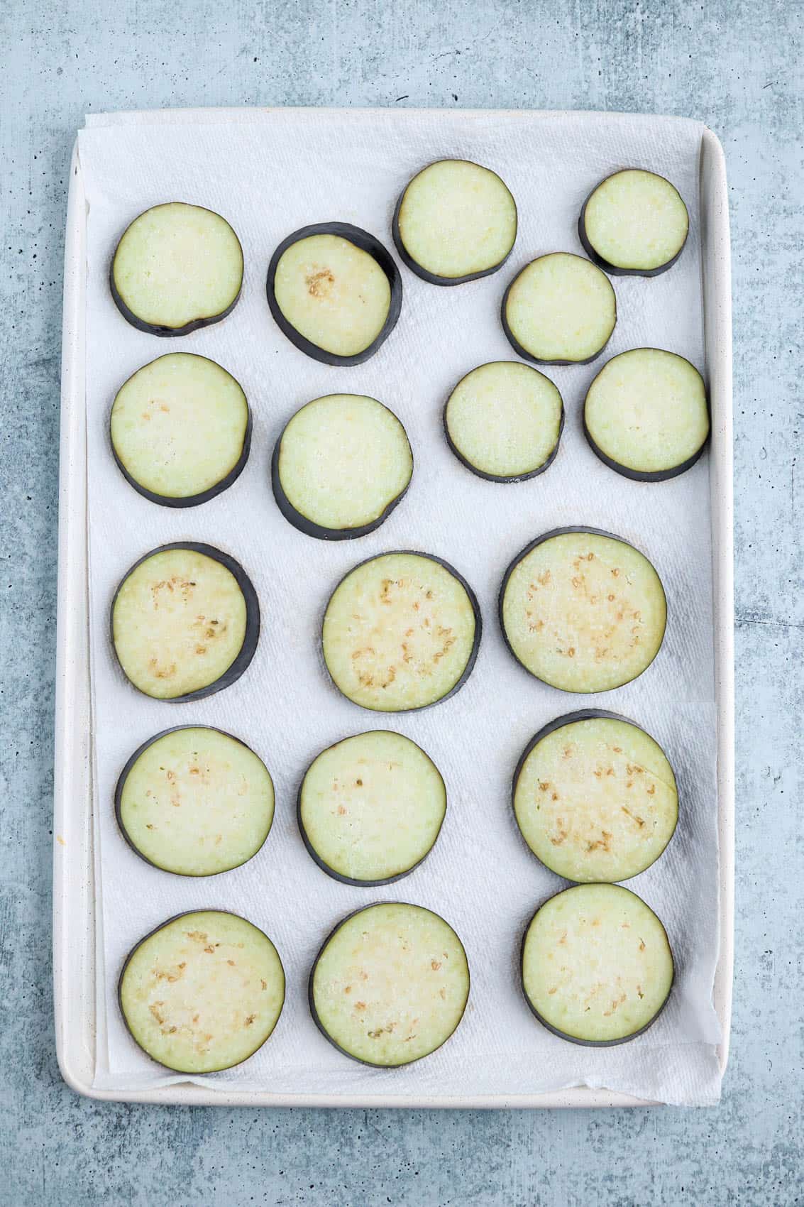 raw eggplant slices on paper towel lined paper towels.