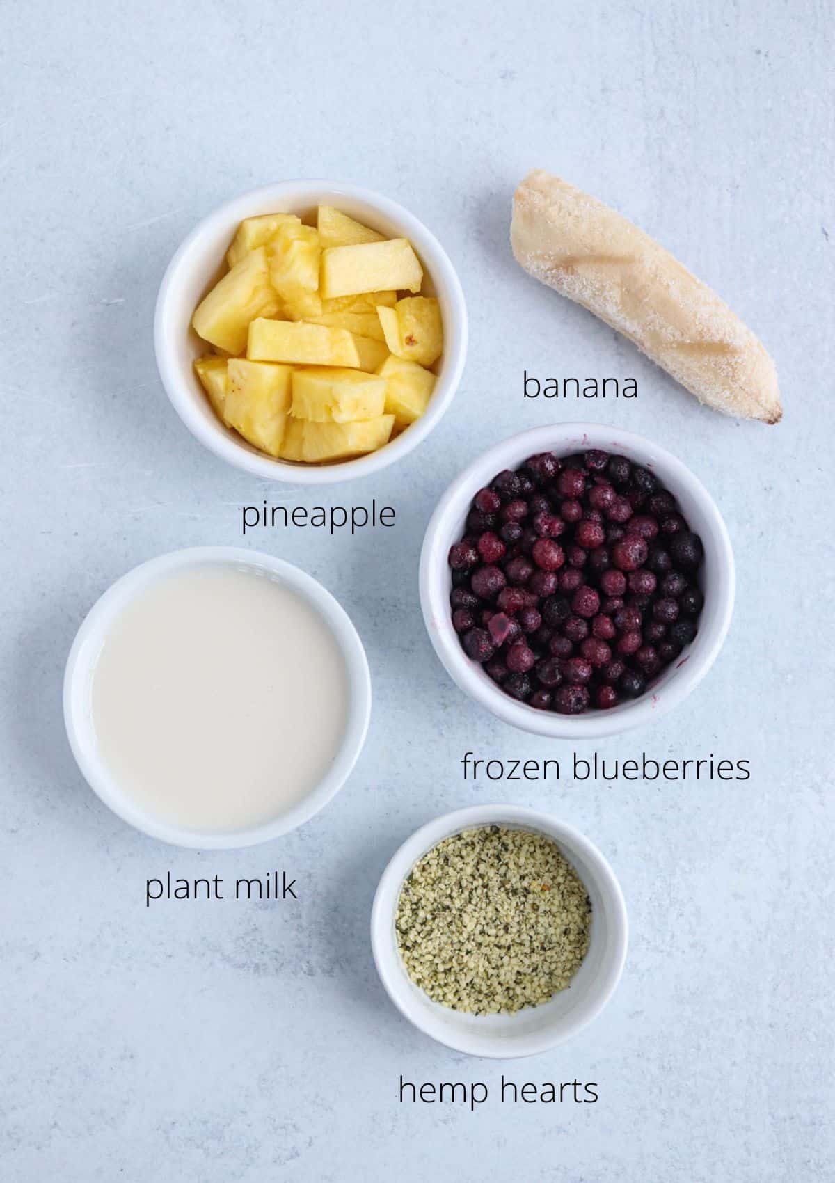 ingredients for making a blueberry pineapple smoothie in containers  with captions. 