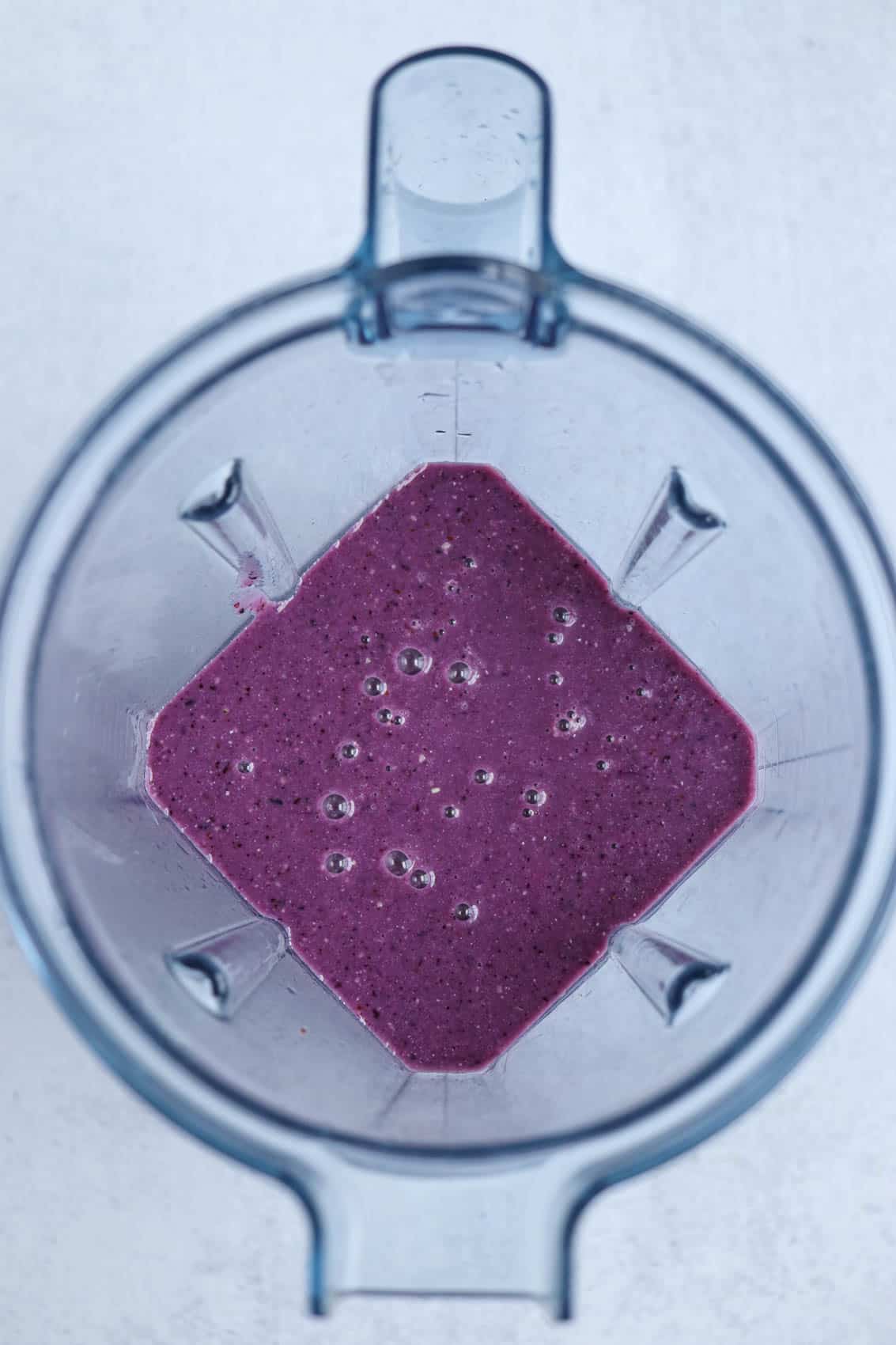 blueberry smoothie blended in a jug of a blender, overhead shot.