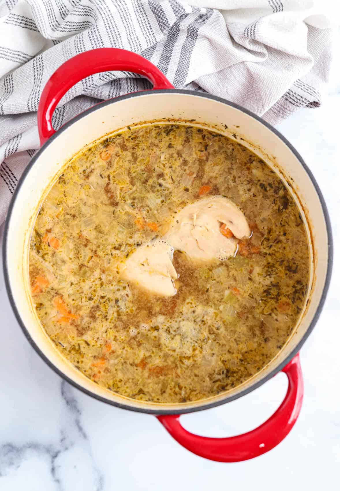 cooking bone broth chicken soup in a red dutch oven.