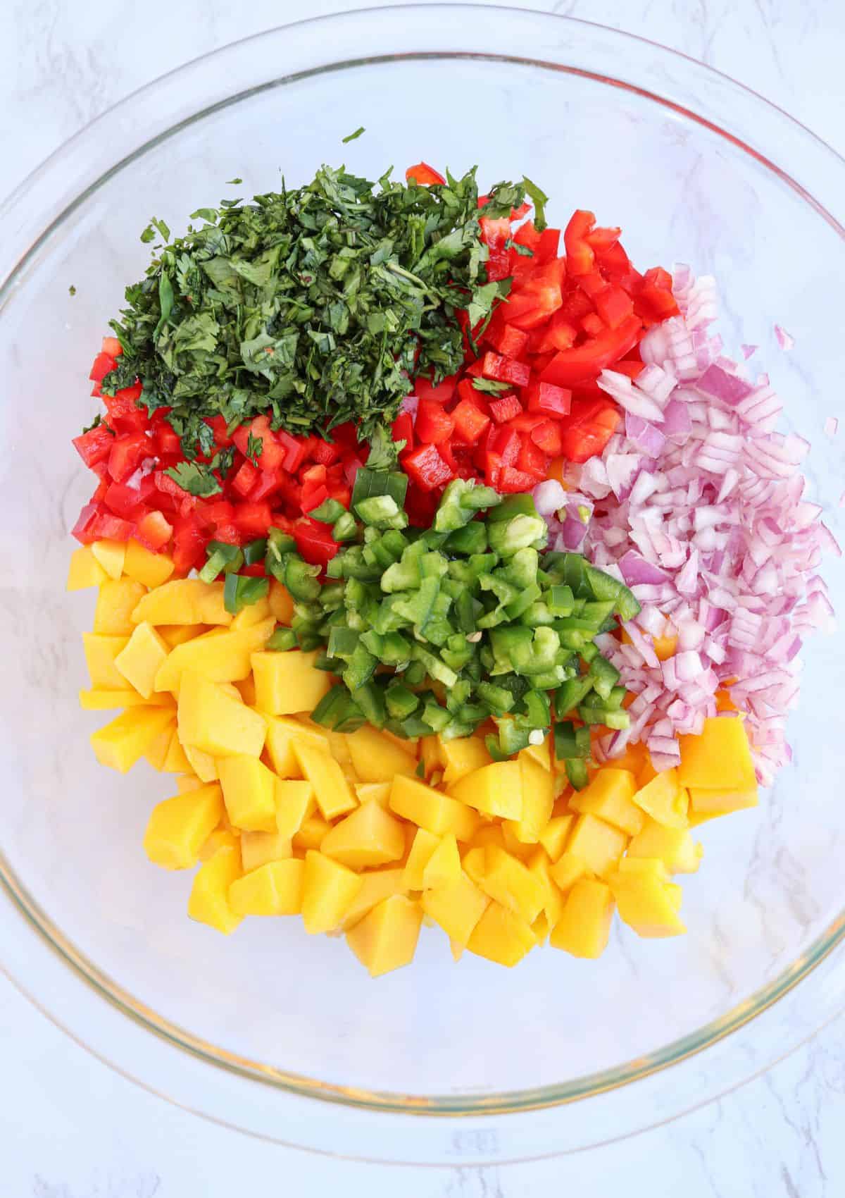 fresh mango salsa in a glass bowl, before mixing.