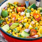 grilled corn salad in a red bowl.