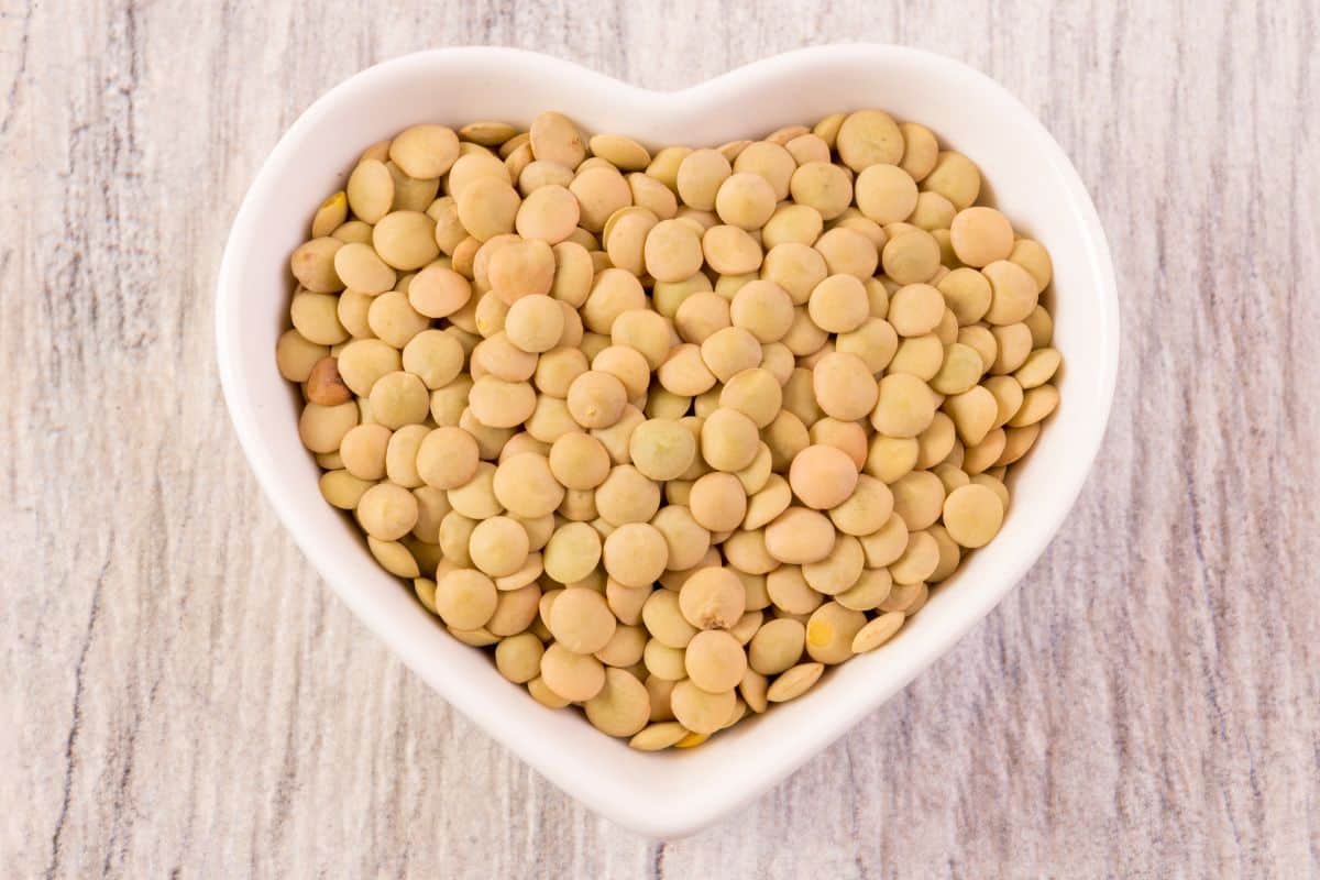 uncooked brown lentils in a heart-shaped bowl.