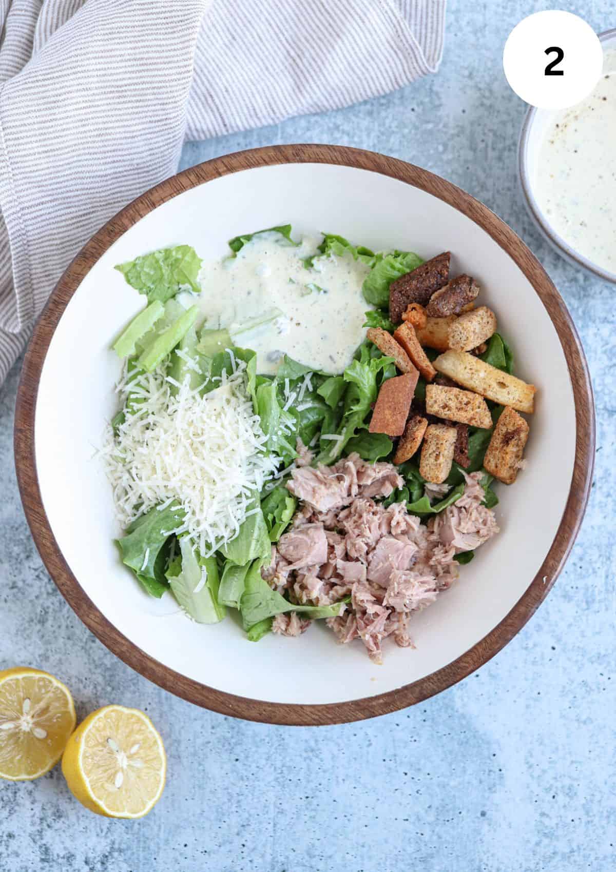 tuna caesar salad ingredients in a bowl before mixing together.
