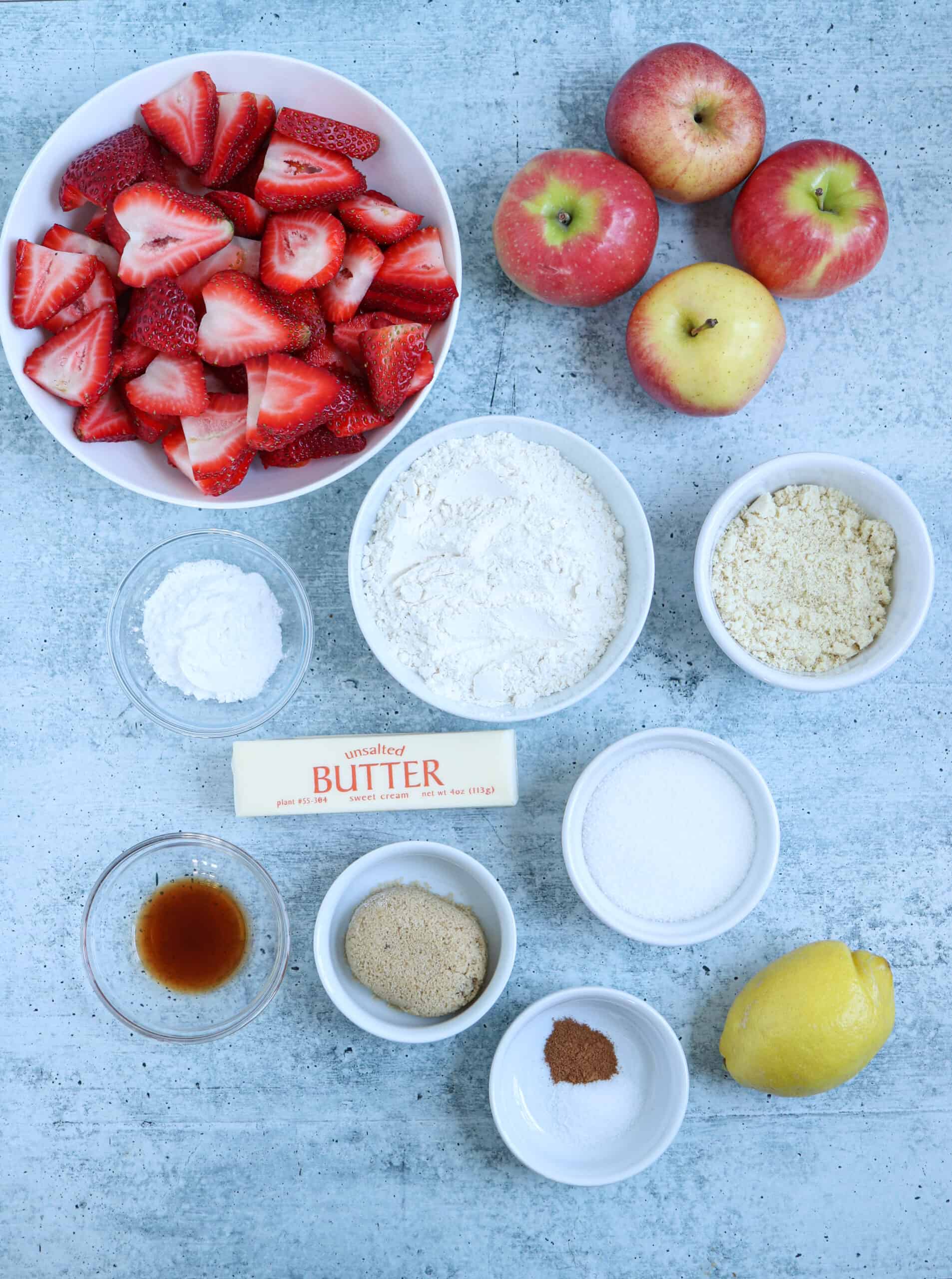 ingredients for making strawberry apple crisp on gray surface.