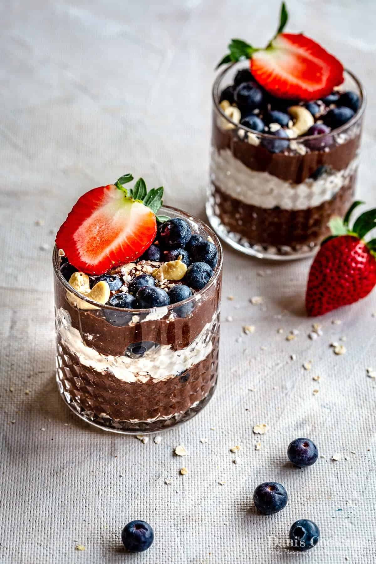 chocolate chia pudding triffle in glasses topped with fresh berries.