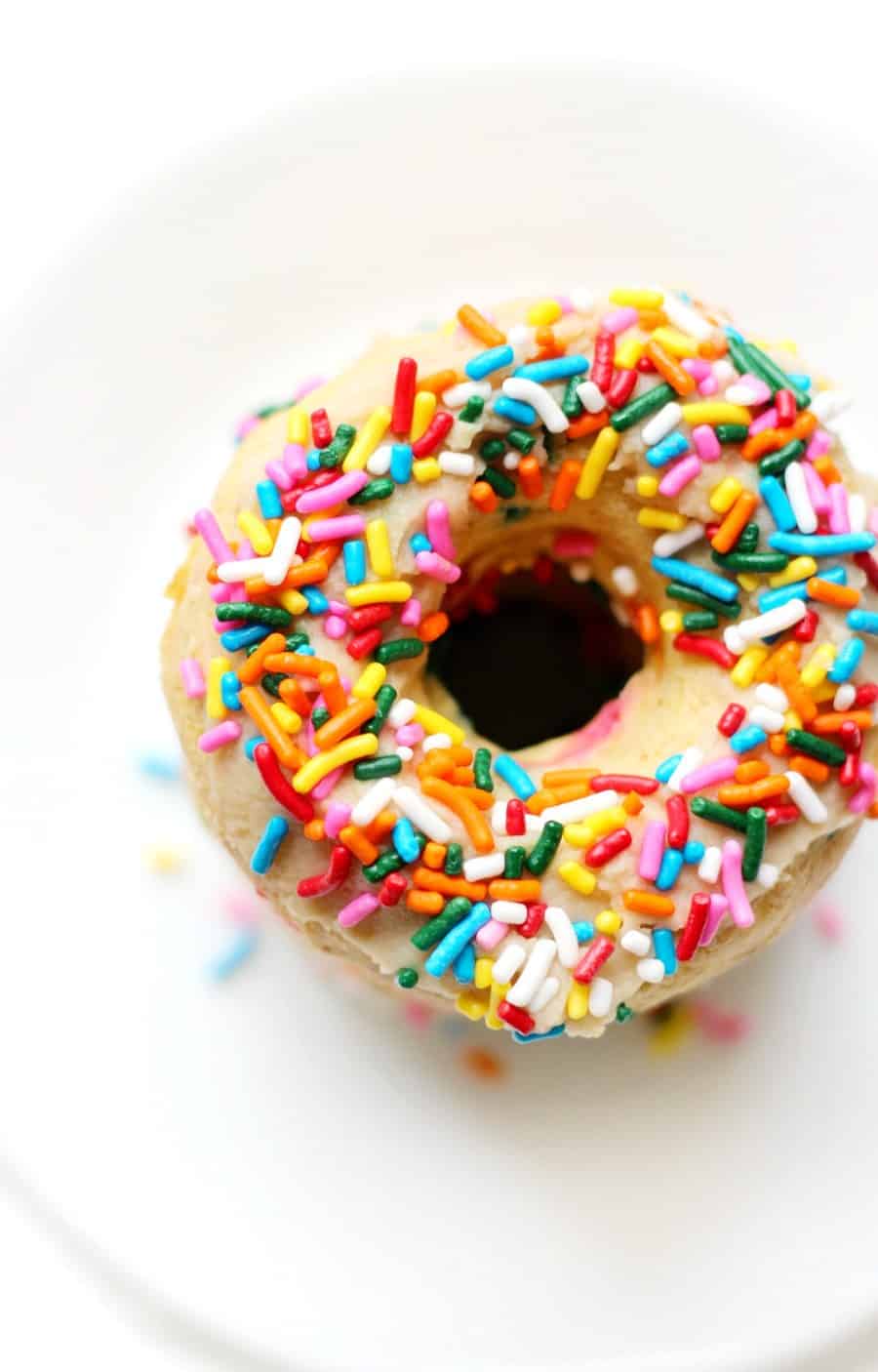 a baked donut topped with rainbow sprinkles.