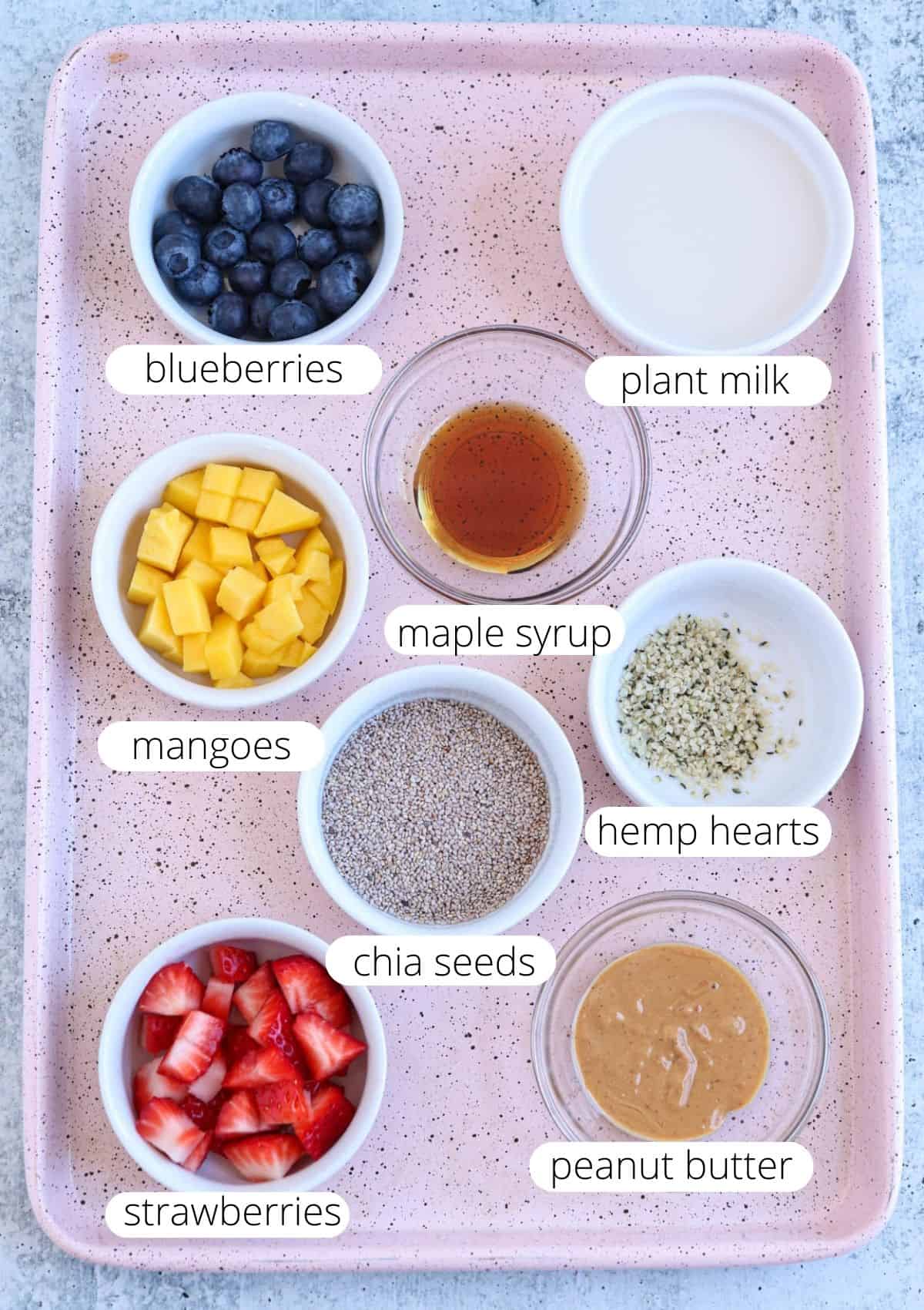 ingredients for making chia breakfast bowl on a pink cookie sheet with captions. 
