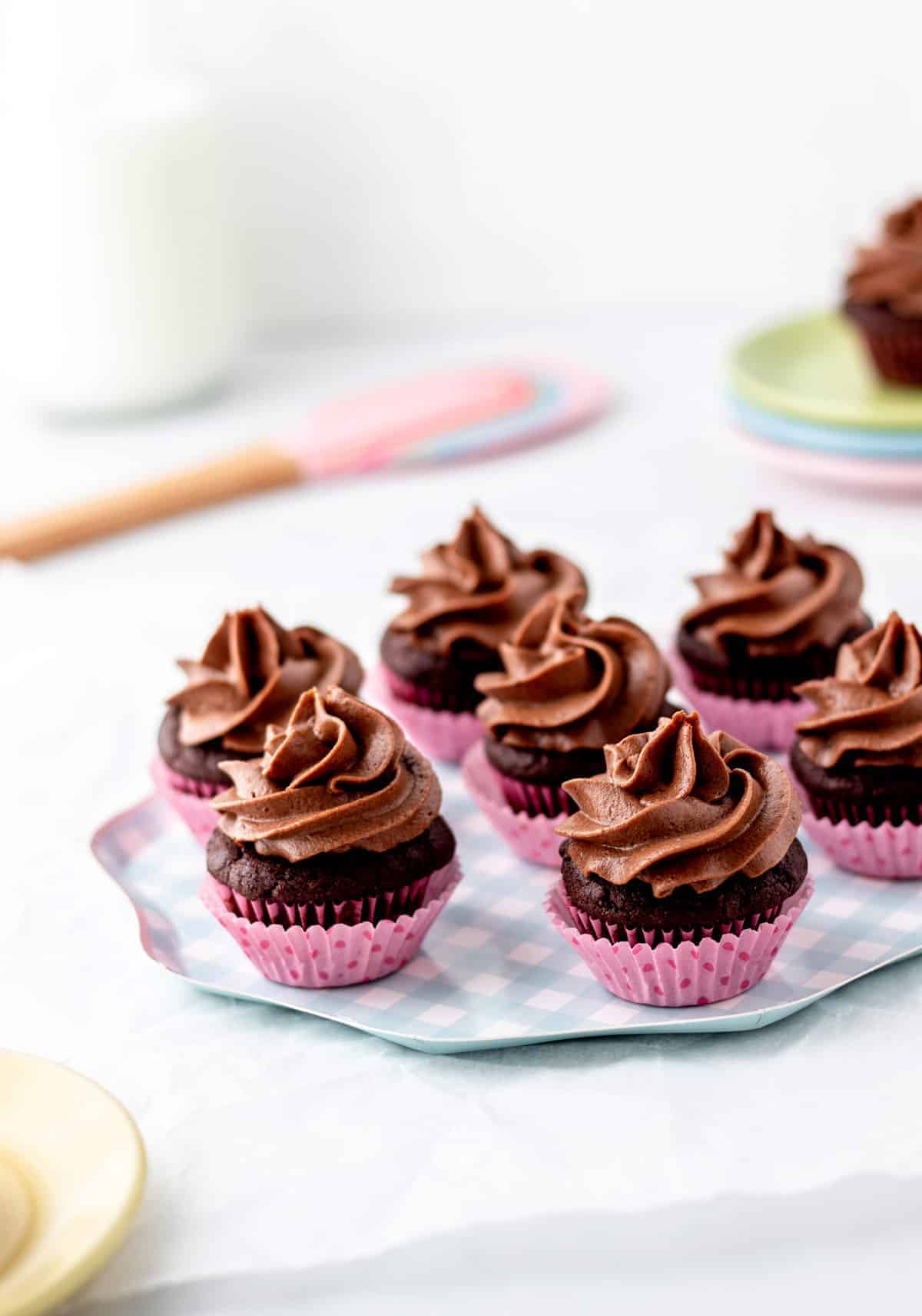 mini chocolate cupcakes in pink muffin liners on a plate.