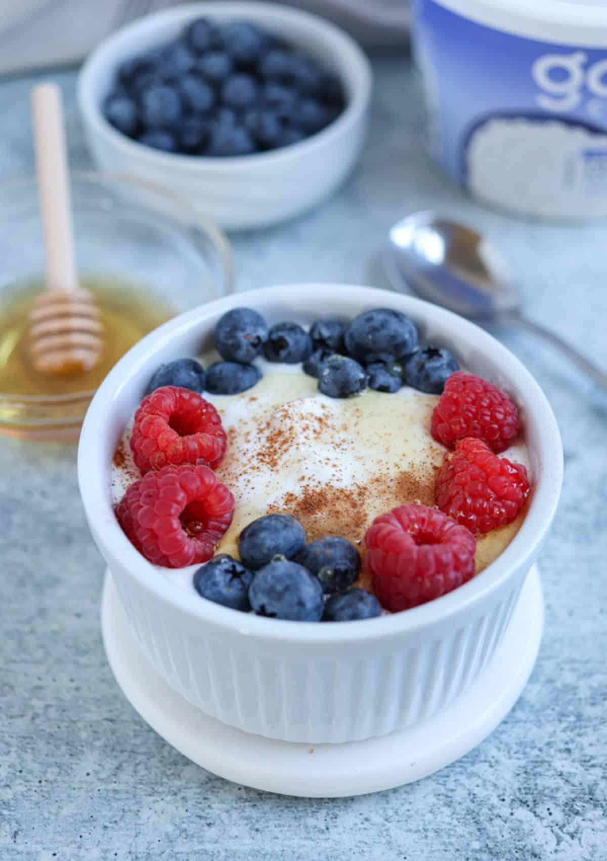 blended cottage cheese in a small ahite ramekin with fresh berries, honey and cinnamon.