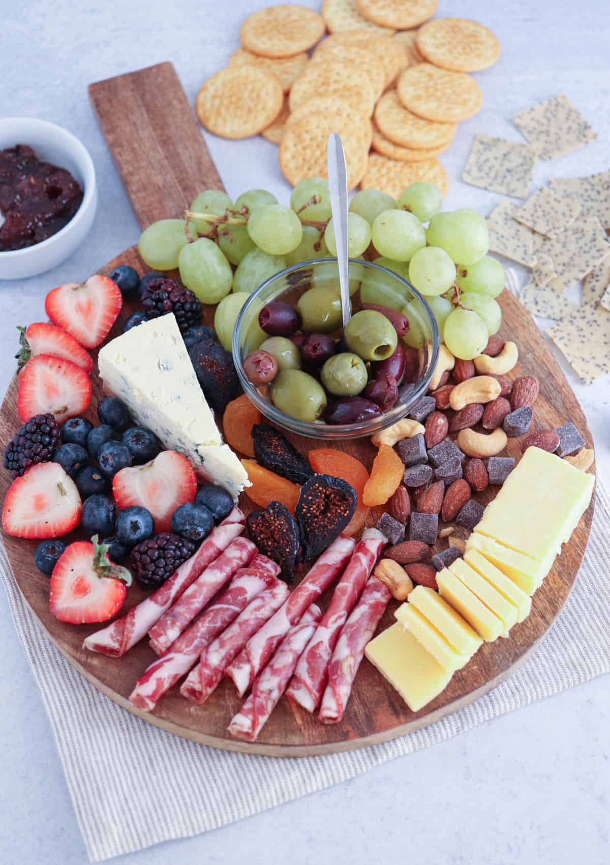 small round charcuterie board with olives.