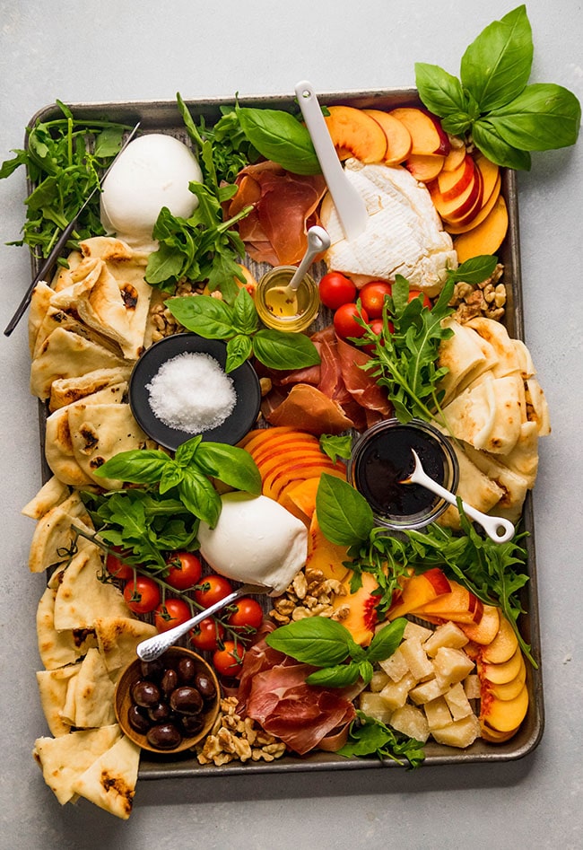summer charcuterie board featuring pita bread, cheese and peaches.