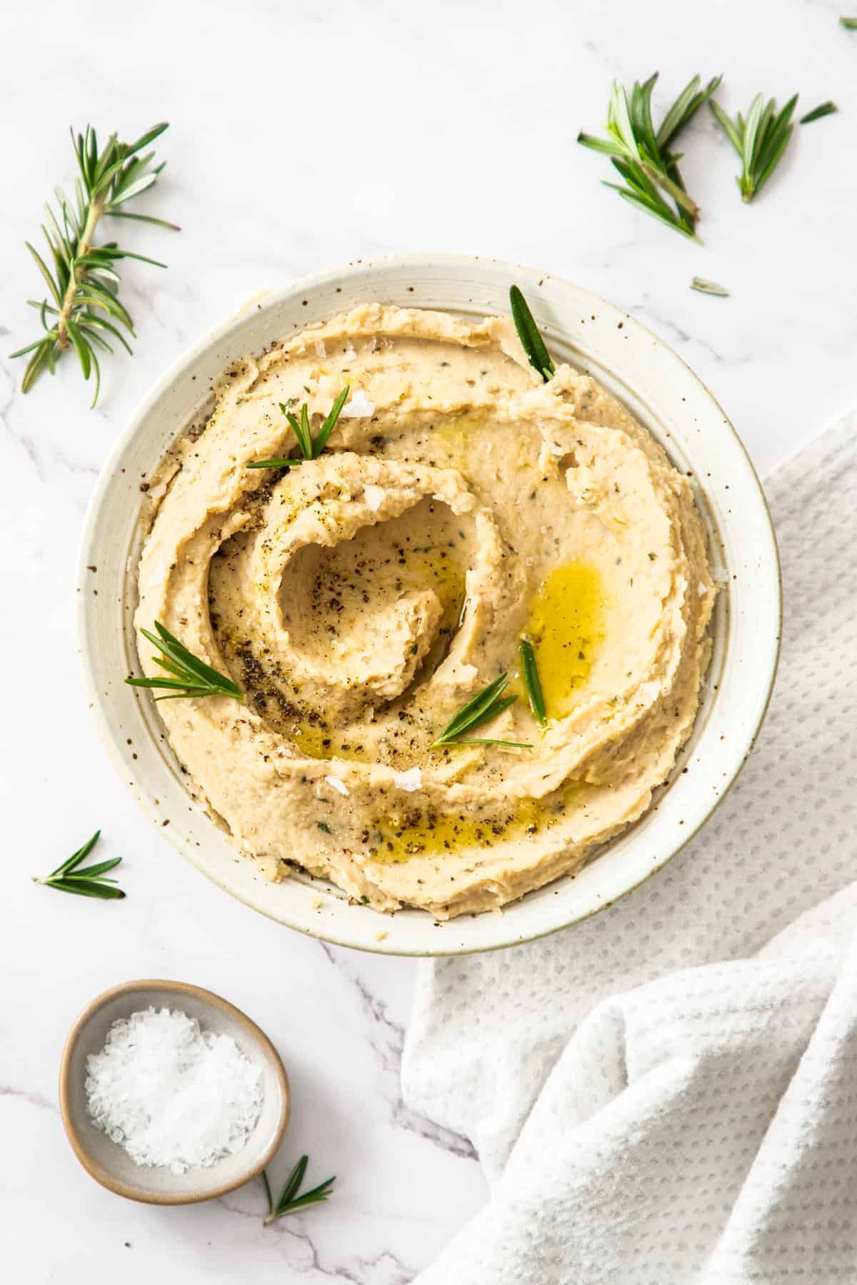 butter bean mash in a white biowl with rosemary. 