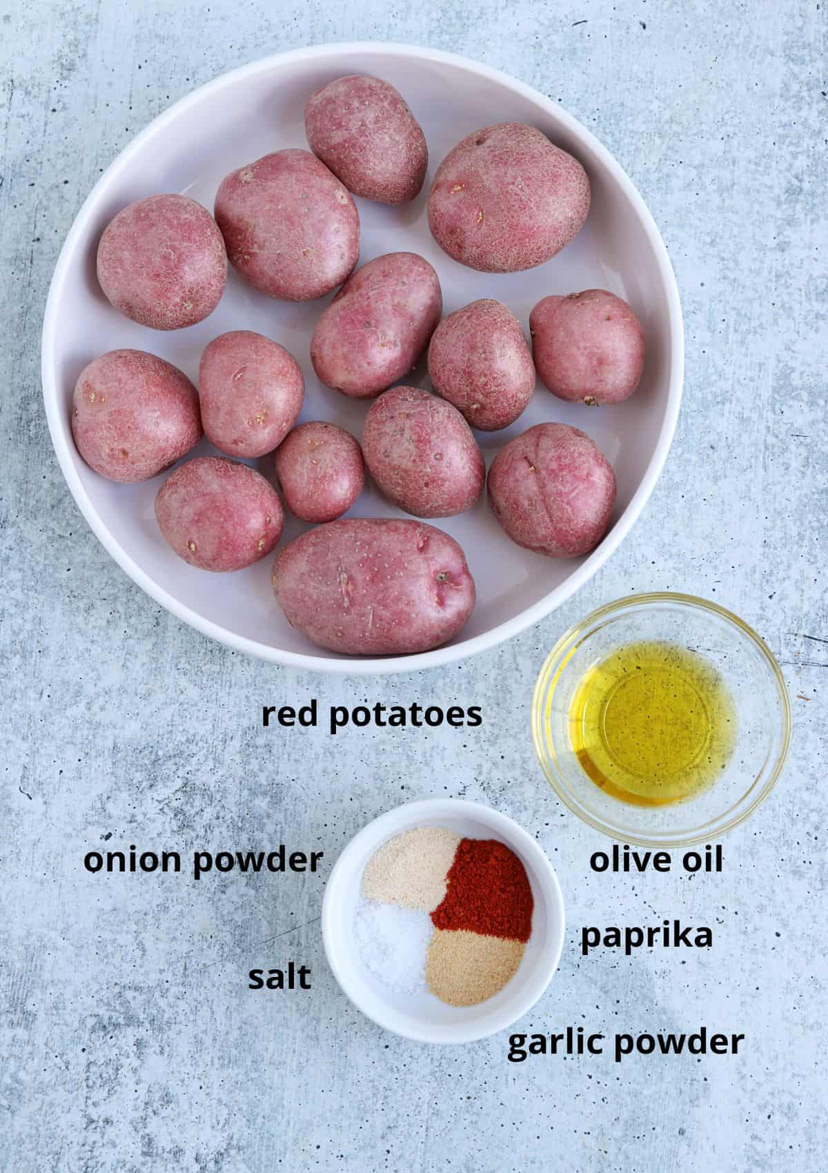 ingredients for making air fryer red potatoes on gray surface with caption.