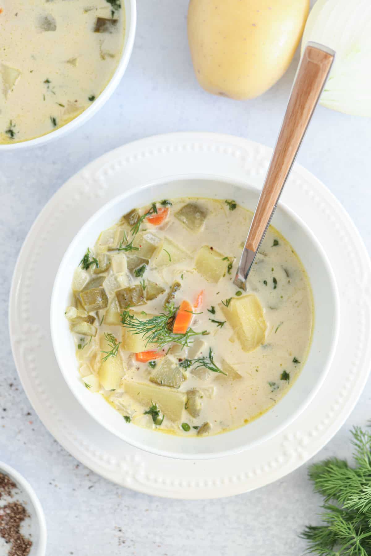 creamy dill pickle soup in a white bowl.