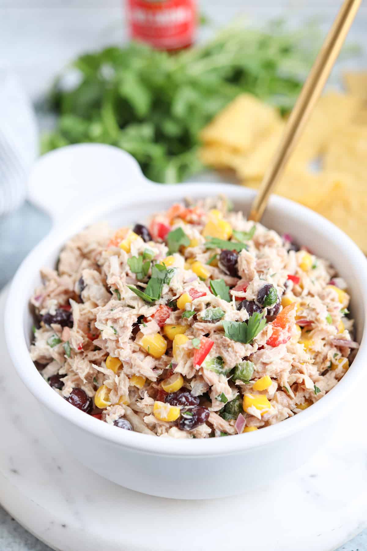 tuna salad with black beans, sweet corn, red peppers and fresh cilantro in a white bowl.