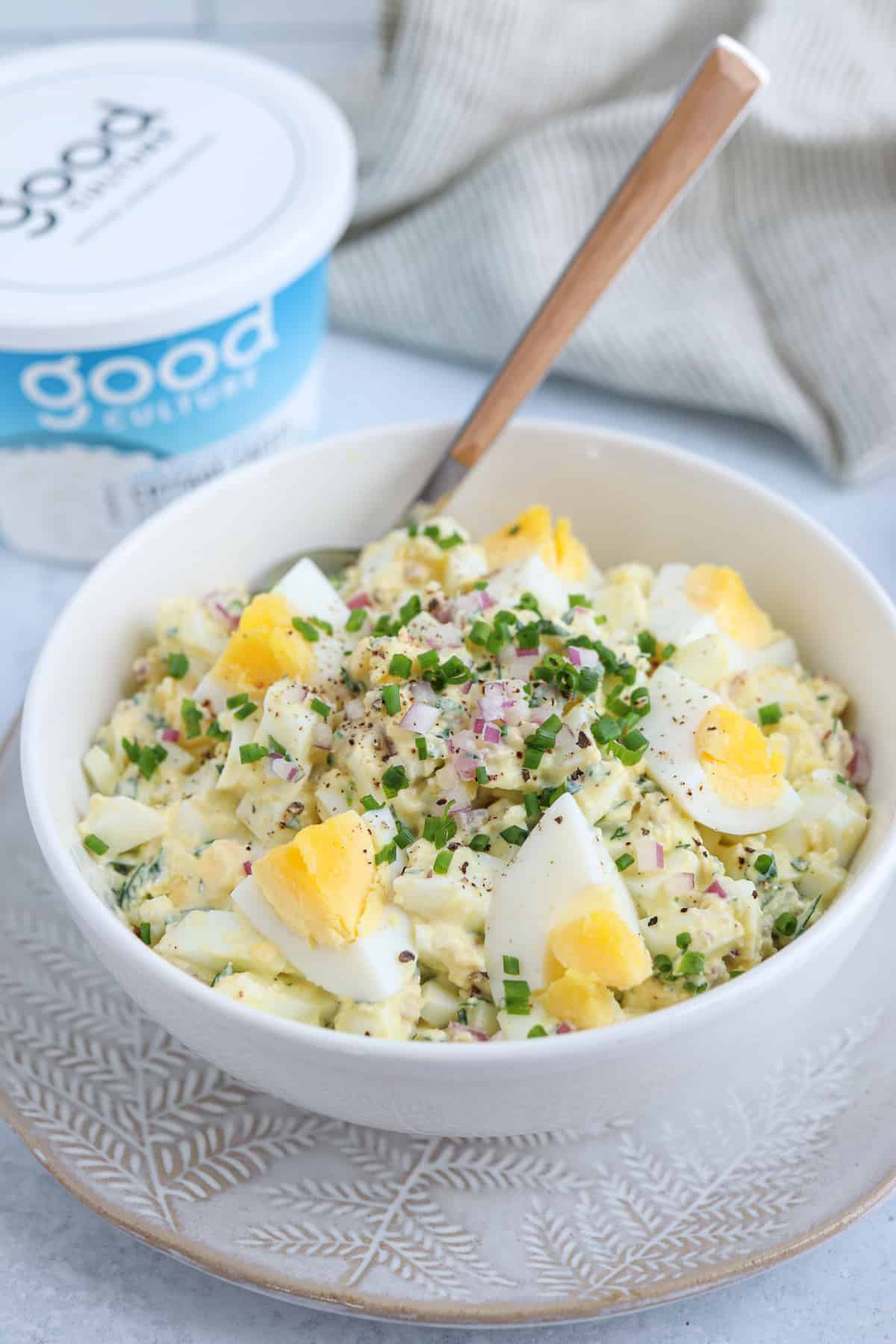 egg salad with cottage cheese, red onion and fresh herbs in a white bowl.