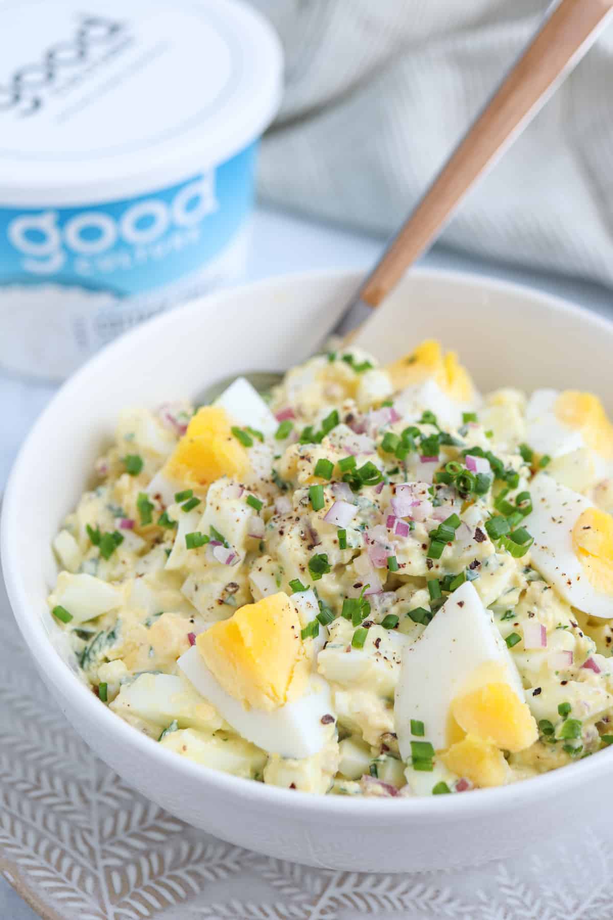 egg salad with cottage cheese, red onion and fresh herbs in a white bowl.