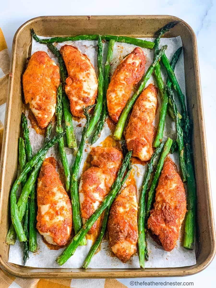 baked chicken tenderloins with asparagus on a sheet pan.