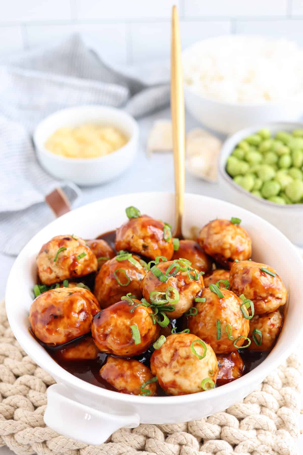 chicken meatballs in teriyaki sauce in a white bowl.