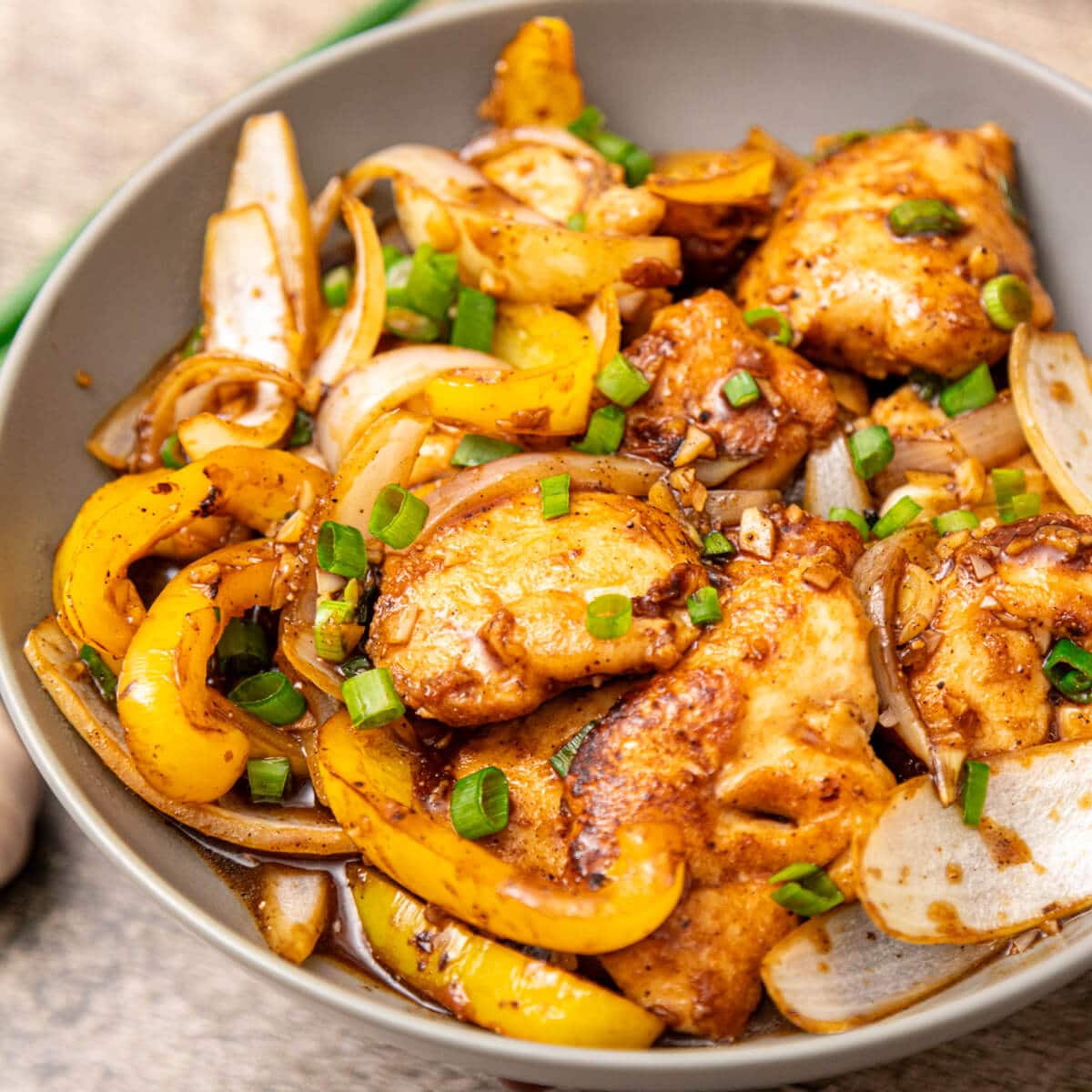black pepper chicken stir fry with peppers and onions in a skillet.