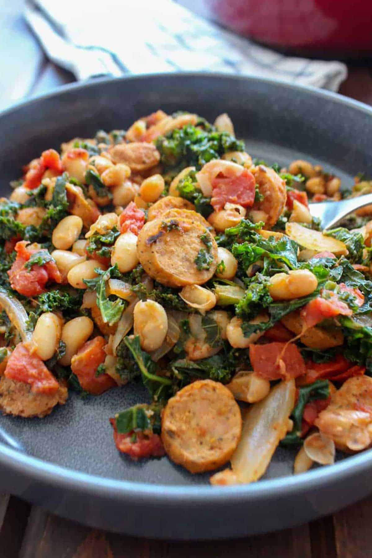 sausage, kale and beans on a blue plate.
