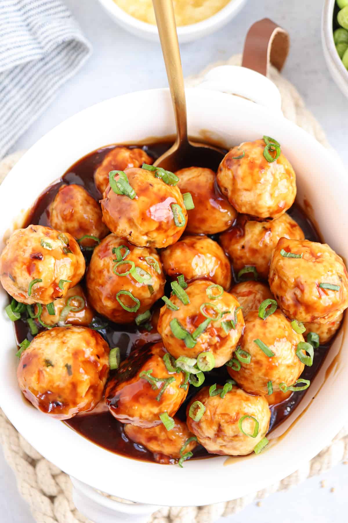 chicken meatballs in teriyaki sauce in a white bowl.