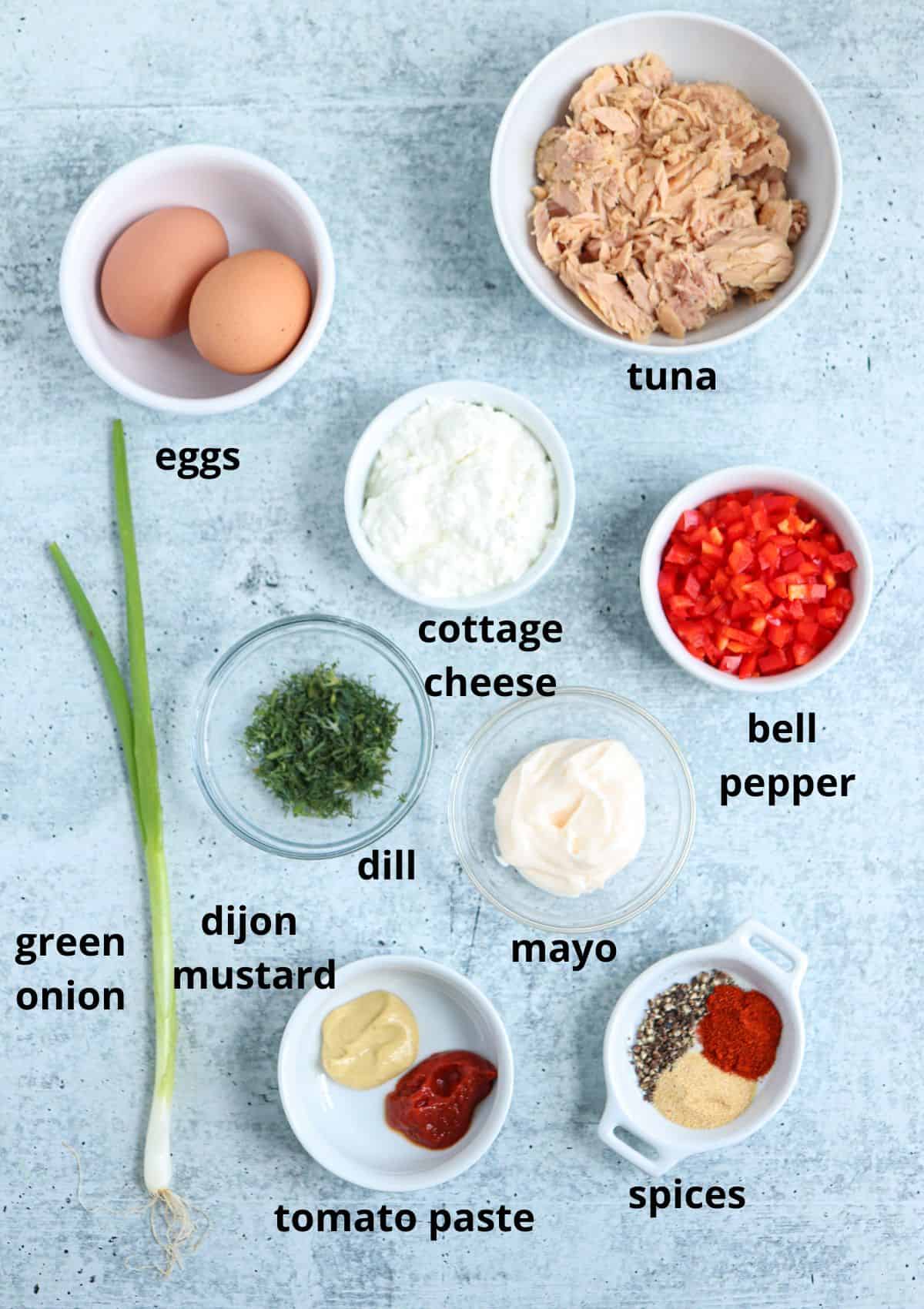 ingredients for making tuna spread on gray surface with captions. 