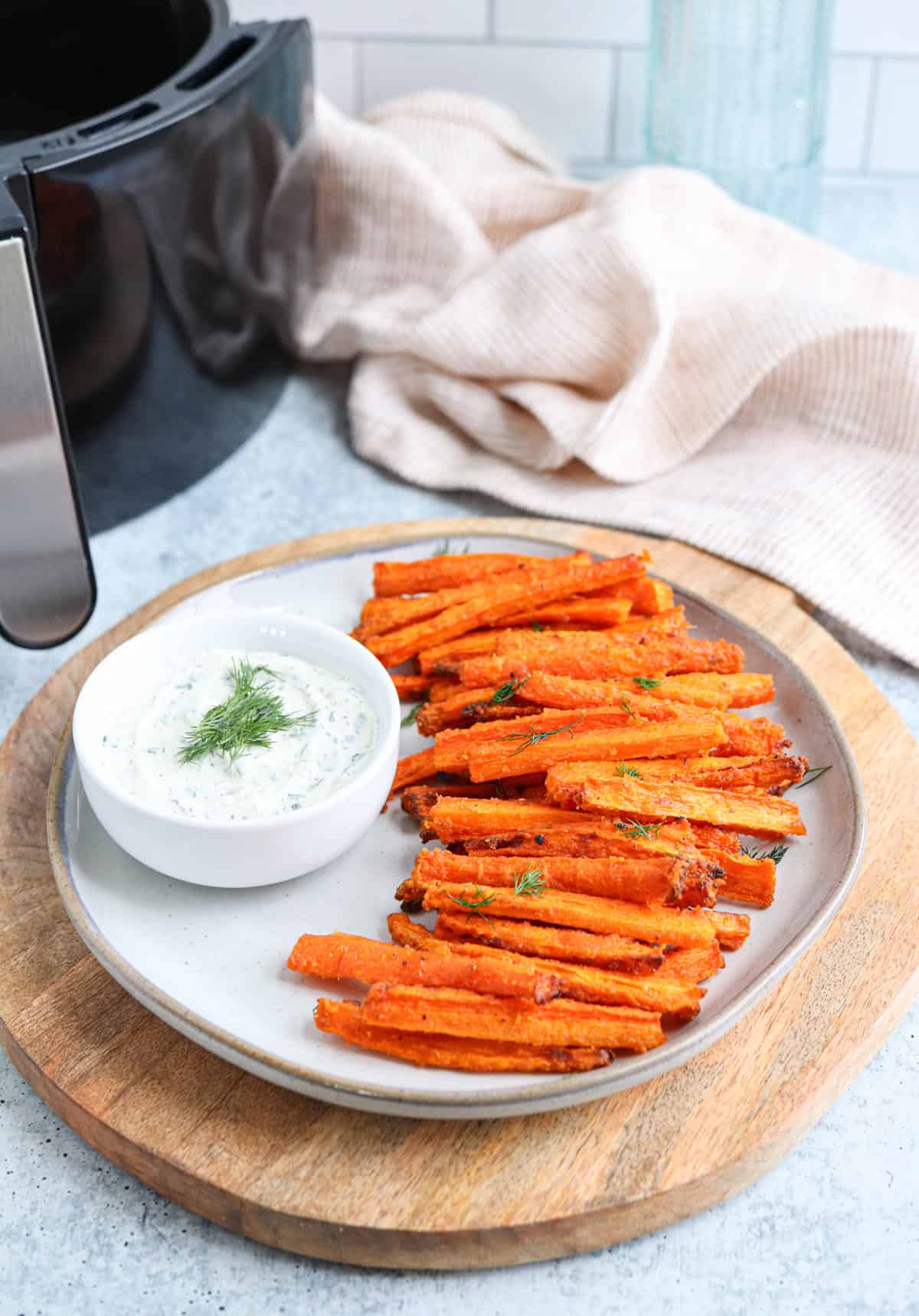 carrot fries on a gray plate with a side of ranch in a small bowl.