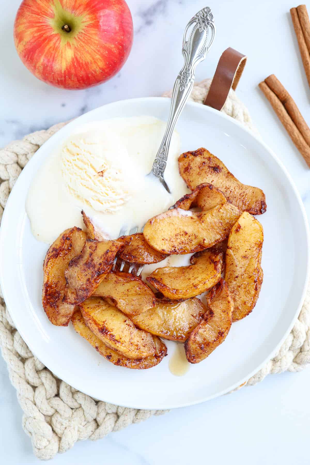 air fried apple slices on a white plate with vanilla ice-cream.