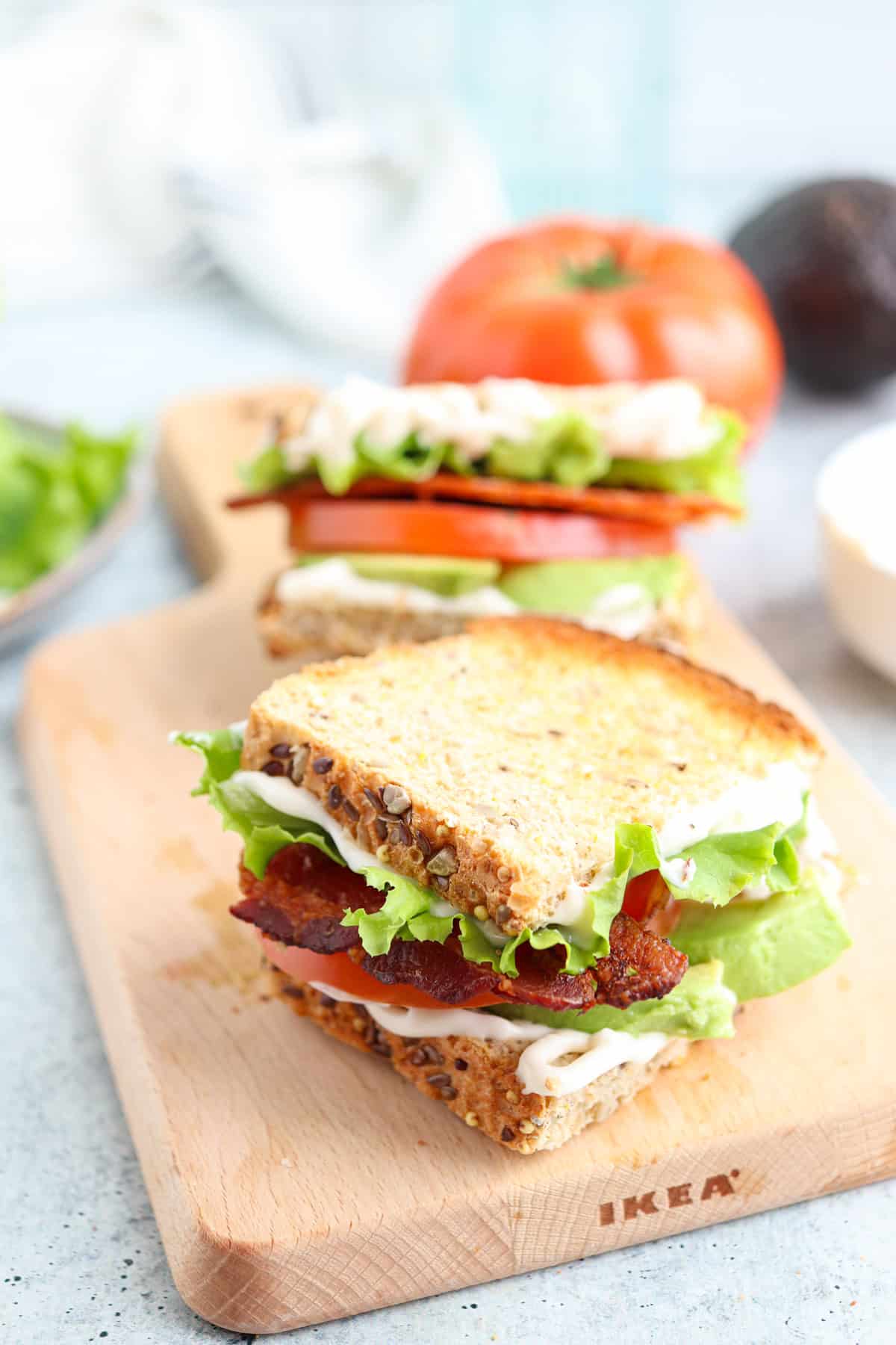 bacon lettuce avocado tomaton sandwich on toasted bread on a wooden board.