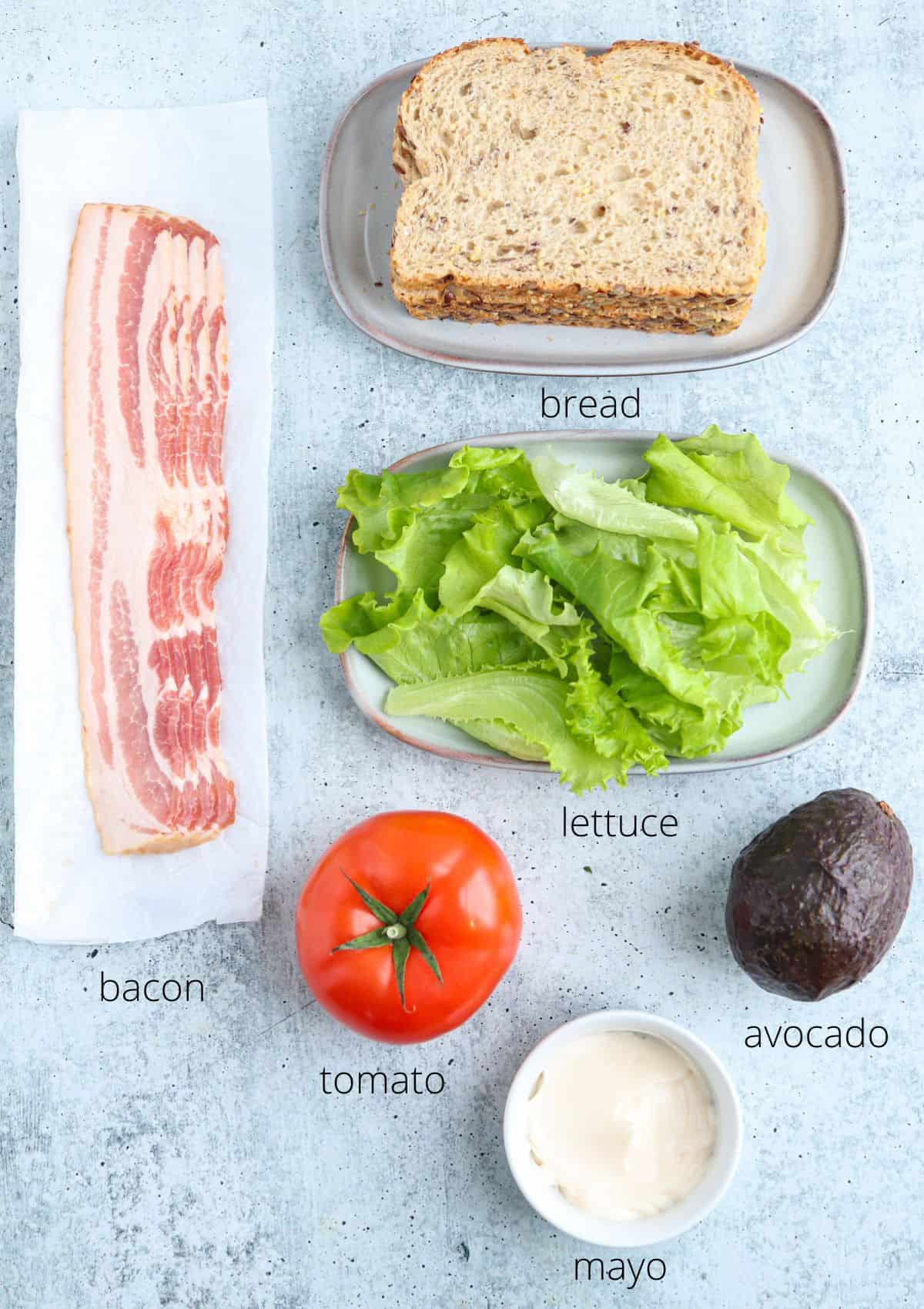 ingredients for making bacon lettuce tomato avocado sandwich with captions.