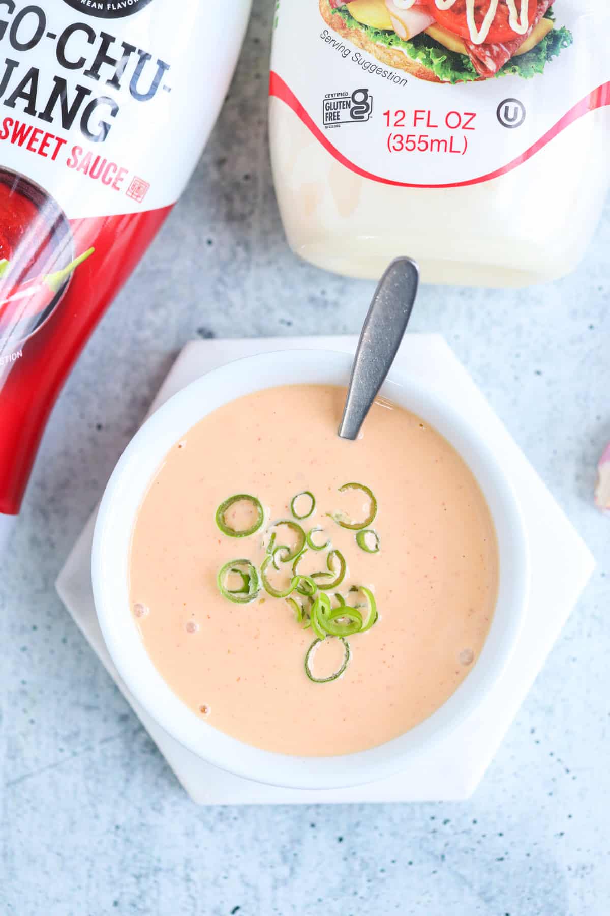 Gochujang aioli in a small white bowl sprinkled with sliced green onions.