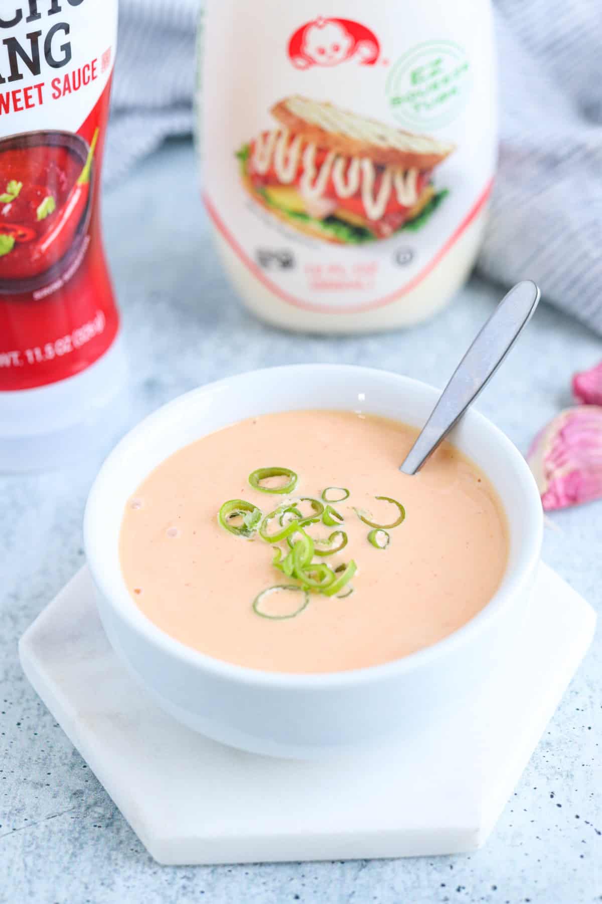 Gochujang aioli in a small white bowl sprinkled with sliced green onions.
