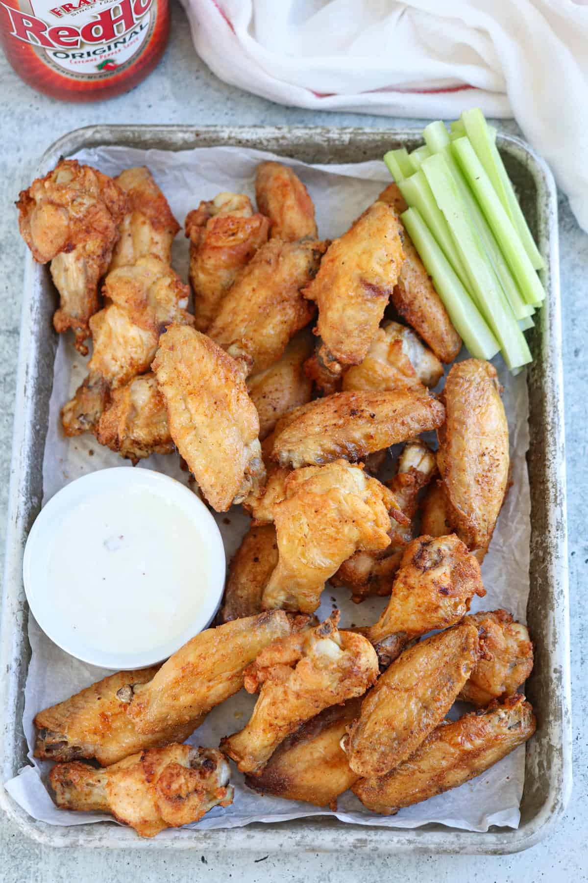 baked chicken wings on a pan with a side of white sauce in a small ramekin.