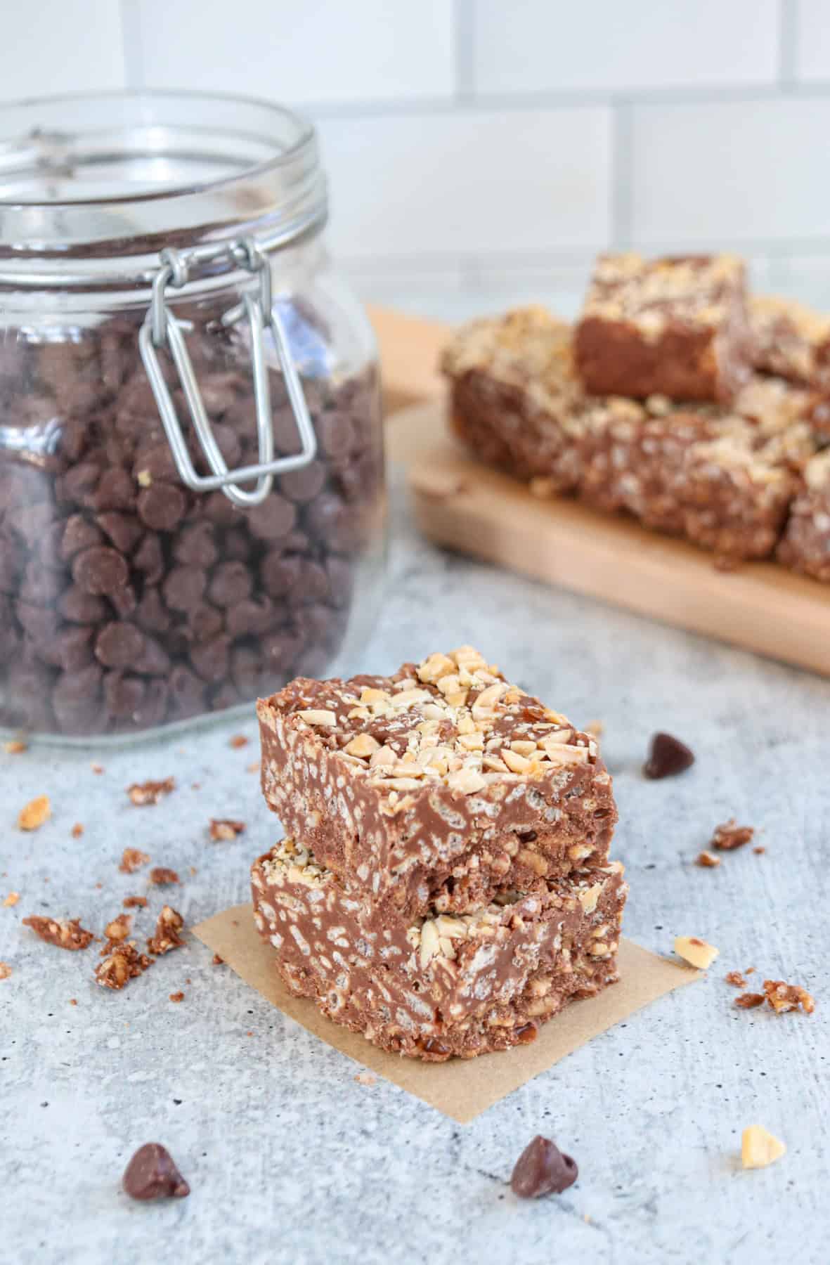 chocolate peanut butter crunch bars stacked on gray surface.