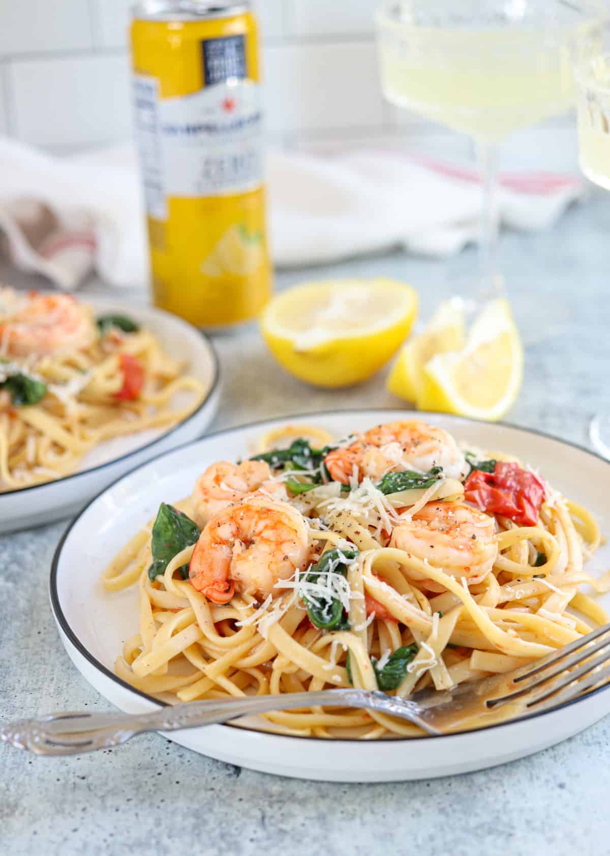 pasta with shrimp, cherry tomatoes and spinach on a plate on gray surface.