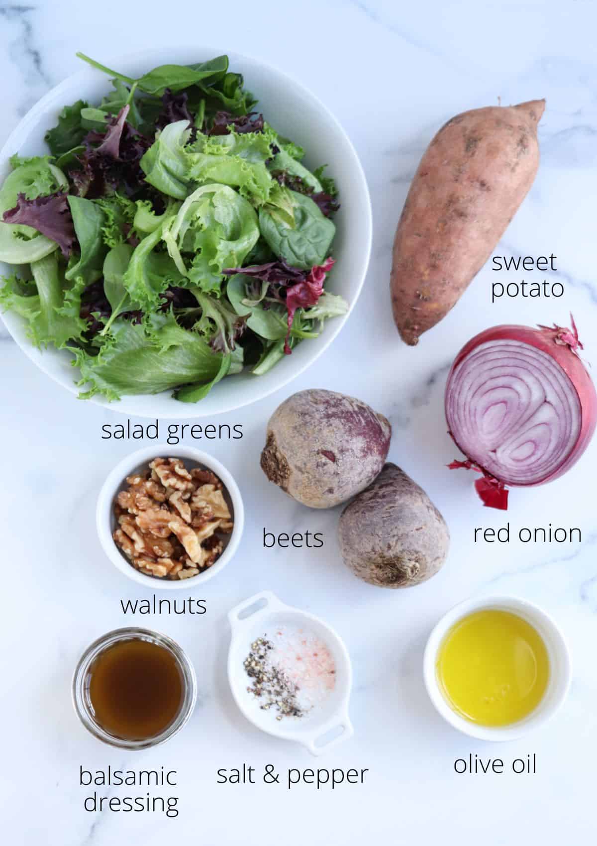 A top-down view showcases the ingredients for a beet and sweet potato salad: a bowl of mixed greens, a sweet potato, two beets, half a red onion, a small dish of walnuts, balsamic dressing, and dishes of salt, pepper, and olive oil. Each item is artfully labeled.