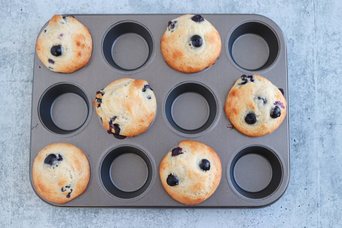 six blueberry muffins in a muffin tin.
