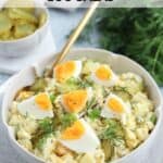 A bowl of dill pickle egg salad topped with quartered boiled eggs and fresh dill, with a fork in the bowl. Sliced pickles and dill are in the background. The text reads: Dill Pickle Egg Salad.